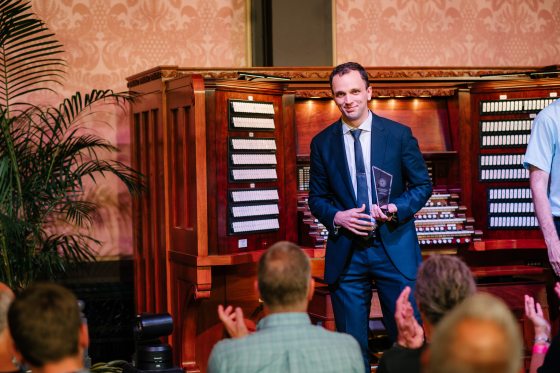 A person in a blue suit walking off the stage of an organ.